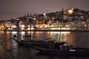 A nighttime view of the Douro River in Porto, with traditional boats floating on the water, romantic Porto wedding